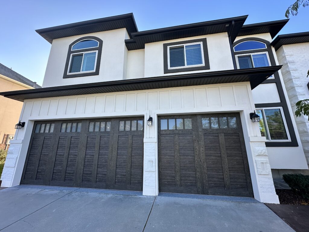 Artisan stucco resurfacing in Holladay, UT featuring a smooth white Senergy finish, high-contrast black soffit and fascia, and custom-engineered stucco board-and-batten trimming around the garage.