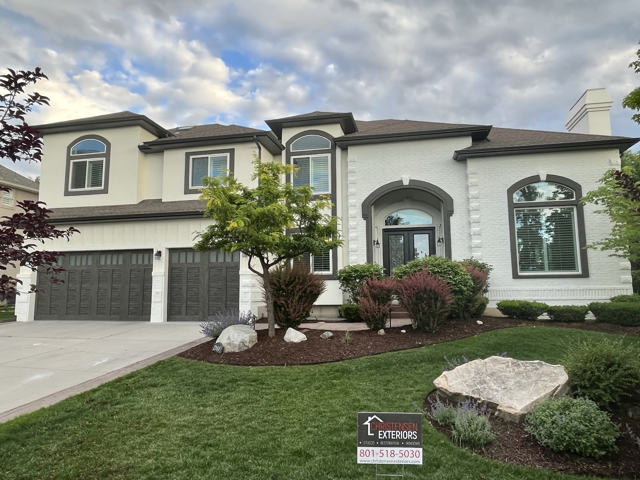 Complete exterior home transformation in Cottonwood Heights, Utah, featuring Arctic White stucco resurfacing, stone masonry accents, and high-performance dark window integration by Christensen Exteriors.