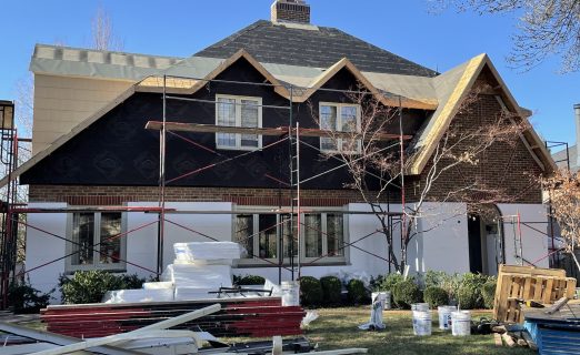 An overview photo of the SLC Avenues home with the old roof removed, showing a clean, bare wood roof structure with new plywood sheeting partially installed.