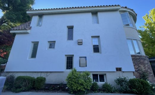 A pristine, sunny daytime photo of the fully remodeled Salt Lake City Avenues home, featuring a seamless, smooth white EIFS stucco exterior and a new terracotta tile roof.